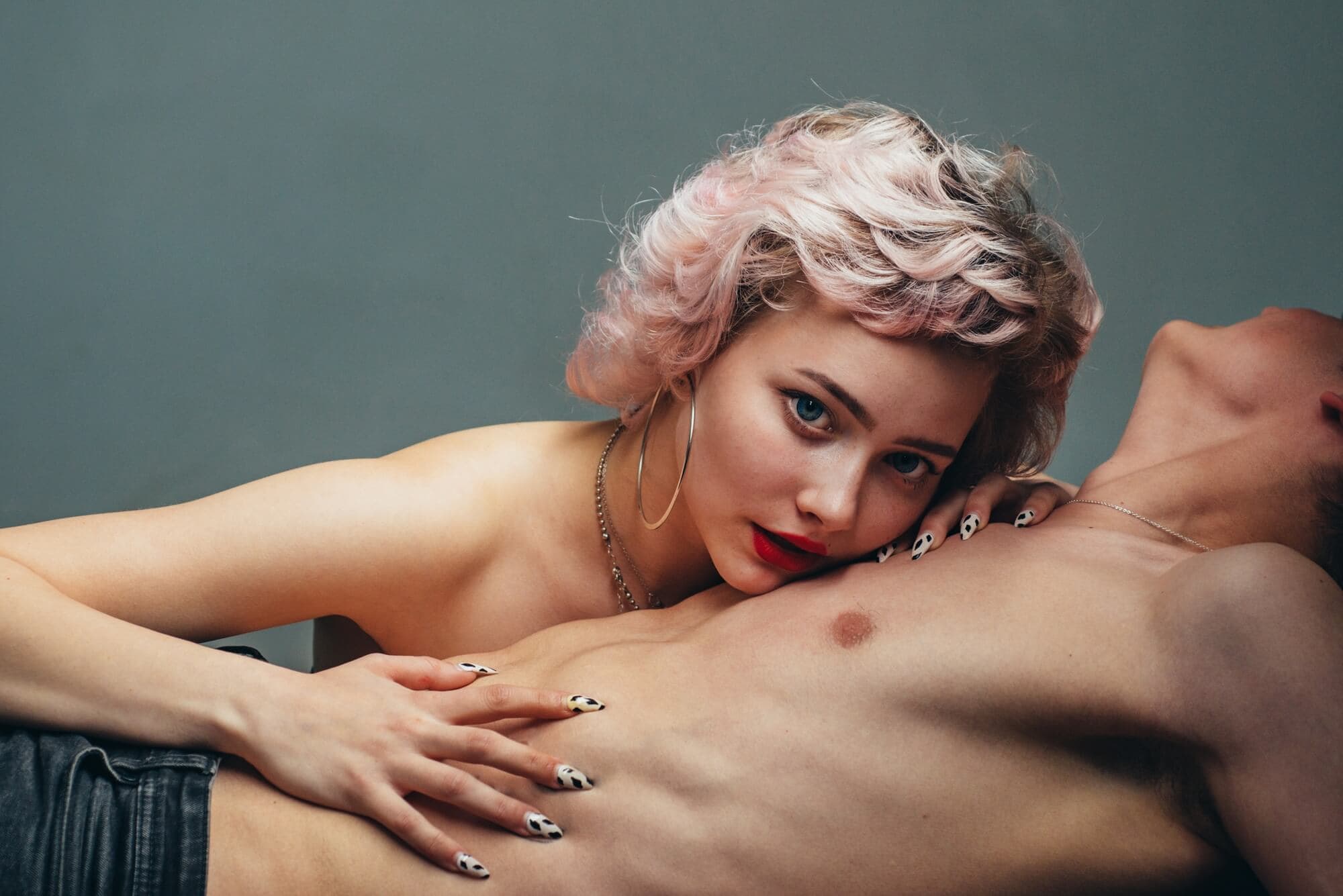 Woman with pink hair lying on man's chest