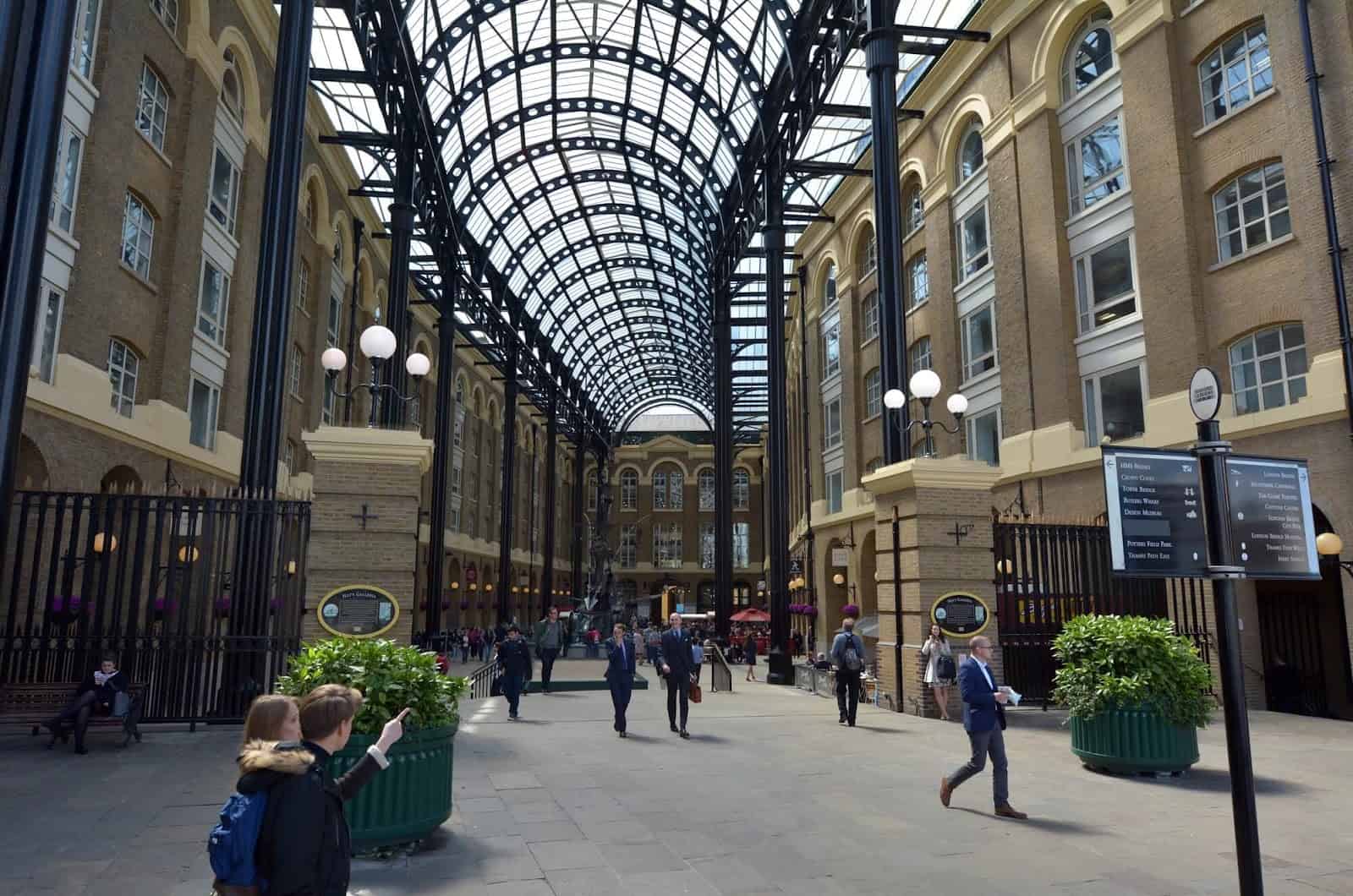 People walking in covered courtyard with arched glass roof.