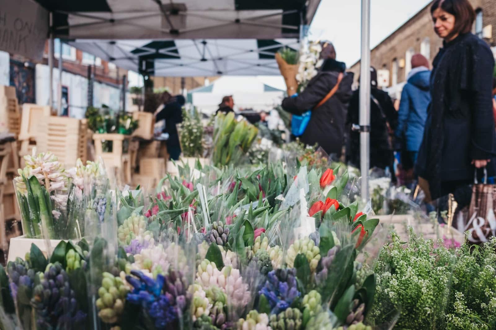 Outdoor flower market with various bouquets and people.