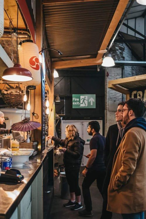People ordering food at a market stall.
