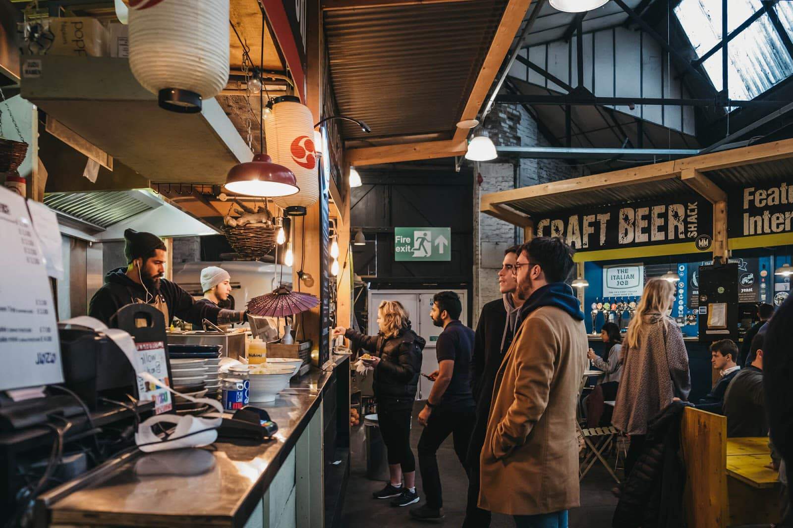 People ordering food at a market stall.