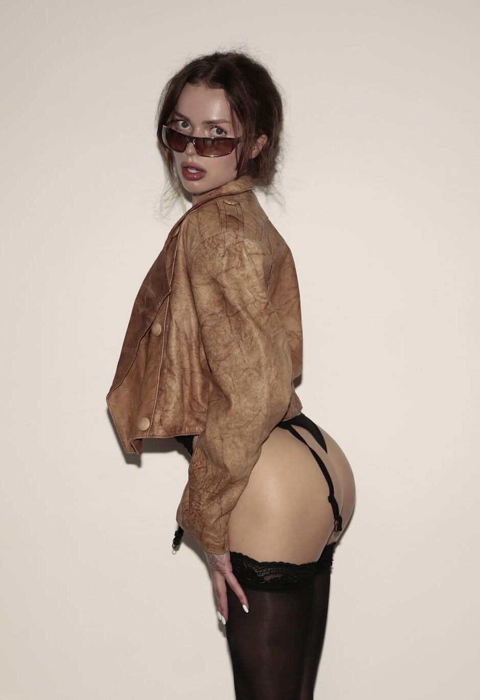 tavria Woman in leather jacket, sunglasses and black stockings posing.