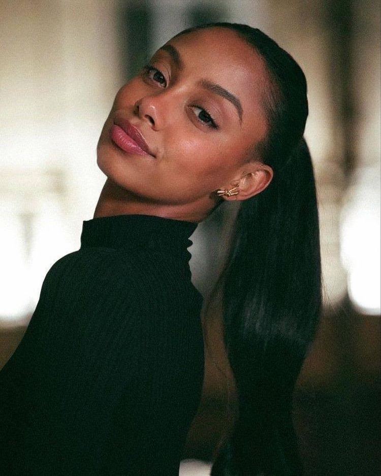 elidi Close-up portrait of a woman with a sleek ponytail.